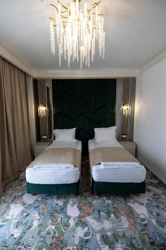 a bedroom with two beds and a chandelier at CHITULESCU Hotel in Târgovişte
