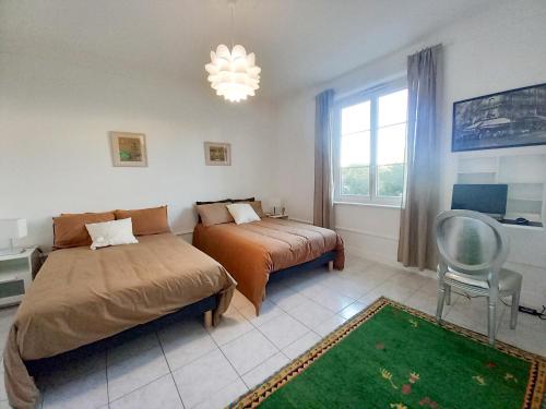 une chambre avec deux lits et une chaise et une fenêtre dans l'établissement Palais Alexandre, à Cannes