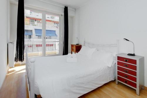 une chambre avec un grand lit blanc et une fenêtre dans l'établissement Jasmine, à Nice