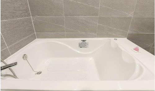 a white bath tub in a bathroom with tiles at H Avenue Gyeongju Bulkuk temple in Gyeongju