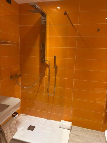 a shower in a bathroom with orange tiles at Blue Shades Hotel in Pisa
