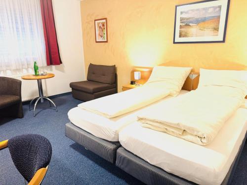 a hotel room with two beds and a chair at Hotel Am Weyerhof in Kerpen