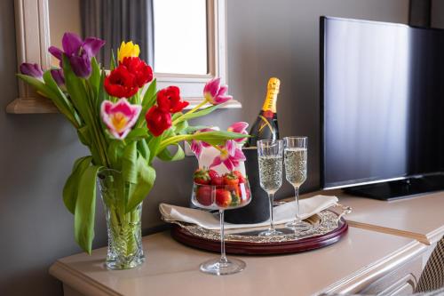 a table with flowers and a bottle of champagne and glasses at Hotel Brilliant Meseș in Zalău