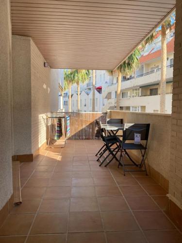 a patio with chairs and a table and palm trees at Apartamento Vigar in Castell de Ferro