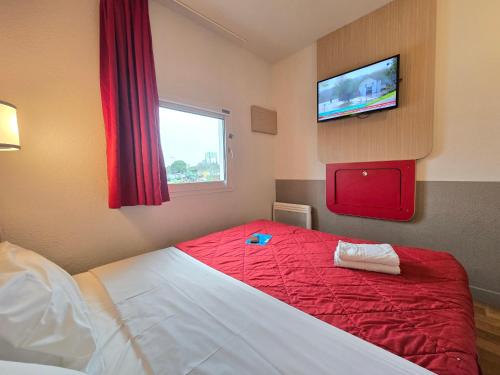 a bedroom with a red bed with a tv on the wall at Premiere Classe Evry Sud - Mennecy in Ormoy