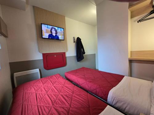 a bedroom with a bed and a tv on the wall at Premiere Classe Evry Sud - Mennecy in Ormoy