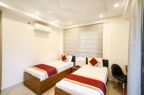 a hotel room with two beds and a chair at FabHotel La Paz Stay B&B in New Delhi