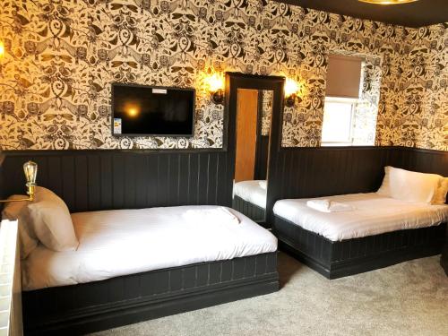 a bedroom with two beds and a tv on the wall at The Residence Sasco Apartments in Blackpool