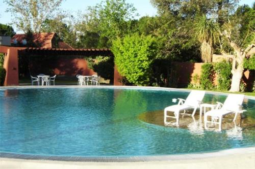 uma piscina com cadeiras brancas num quintal em Robles de Besares em Chacras de Coria