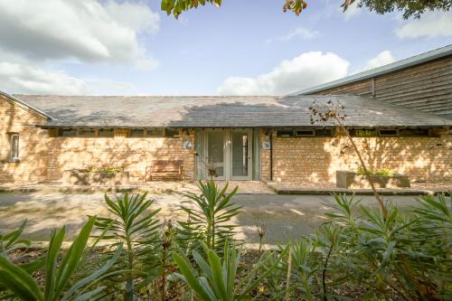 an old brick house with a white door at Hares Scrape at Tove Valley Cottages in Towcester