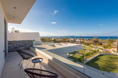 a balcony with two chairs and a view of the ocean at Aethra Villas Luxury Retreat in Anissaras
