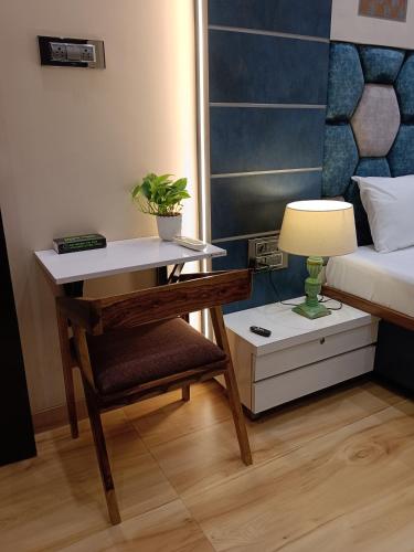a bedroom with a desk and a bed and a lamp at Satya Stays Premium Boutique Apartment in Navi Mumbai