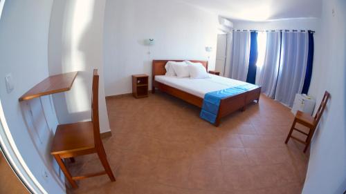 a bedroom with a bed and a table and chairs at Cacimba Sunset Lodge in Tarrafal