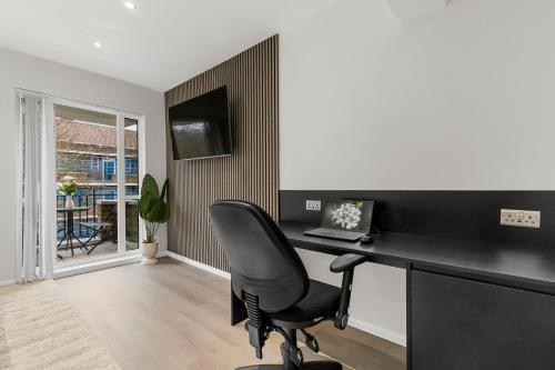 a office with a black desk and a chair at Jasmine Suite by Yielding Bricks in London