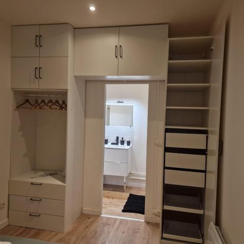 un dressing avec des armoires blanches et un miroir dans l'établissement Bel appartement cosy, à Fleury-les-Aubrais