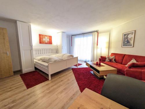 a living room with a bed and a red couch at 4104 Stilvoll eingerichtetes Studio mit Suedbalkon in Vulpera