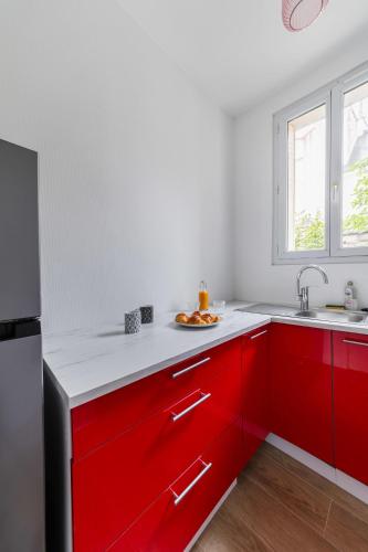 une cuisine avec des armoires rouges et un évier dans l'établissement Appartement 40m2 Parc des Expositions - 6P - FLAT-GUEST, à Malakoff