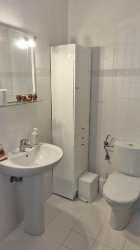 a white bathroom with a sink and a toilet at Coastal maisonette in Nea Potidaea