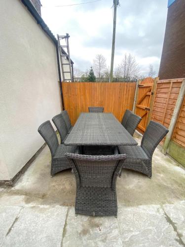 a patio table with chairs and a wooden fence at 5 bedroom Luxury Townhouse near City Centre, sleep 16 in Manchester