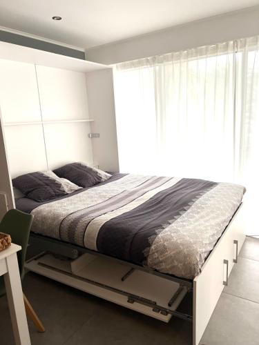 un lit dans une chambre avec une grande fenêtre dans l'établissement Studio Le Saint Honorât Juan les pins, à Antibes