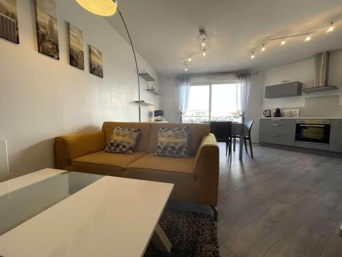 un salon avec un canapé et une table et une cuisine dans l'établissement Appartement- 3 pièces AYTRE - LR590-023, à Aytré
