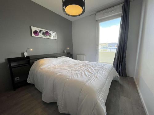 une chambre avec un lit blanc et une fenêtre dans l'établissement Appartement- 3 pièces AYTRE - LR590-023, à Aytré