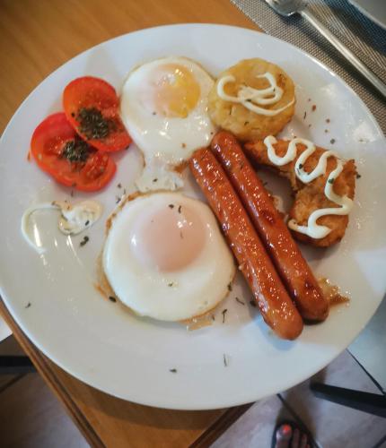 a plate of breakfast food with eggs sausage and tomatoes at A Cherry Lane Self Catering and B&B in Bloemfontein