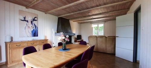 une salle à manger avec une table en bois et des chaises violettes dans l'établissement Pavillon individuel plain-pied avec terrasse et parking, à Saint-Vigor-le-Grand
