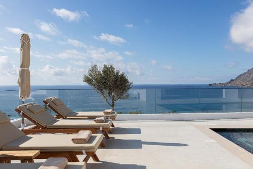 a pool with two lounge chairs and an umbrella at Rokkea Villa in Plakias