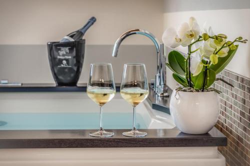 two glasses of white wine and a vase with flowers at Relais Barchessa Molon in Campo di Pietra