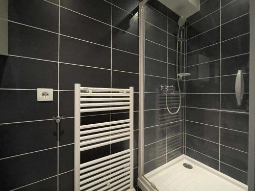 La salle de bains est pourvue de carrelage noir, d'une douche et d'une baignoire. dans l'établissement Appartement T2 à La Rochelle - LR180-004, à La Rochelle