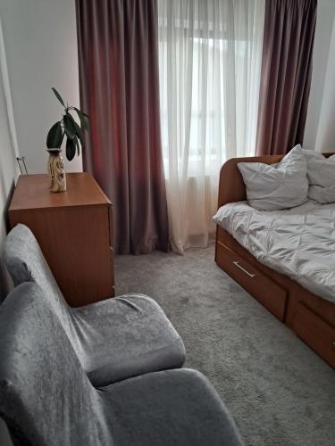 a bedroom with a bed and a chair next to a bed at Căsuța galbenă in Bucharest