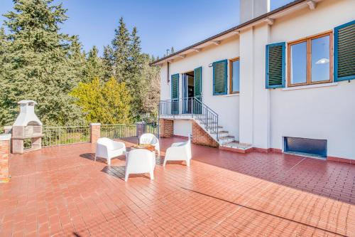 un patio con sillas blancas y una mesa en Homes Boccaccio Beautiful Terrace - Happy Rentals, en Montespertoli