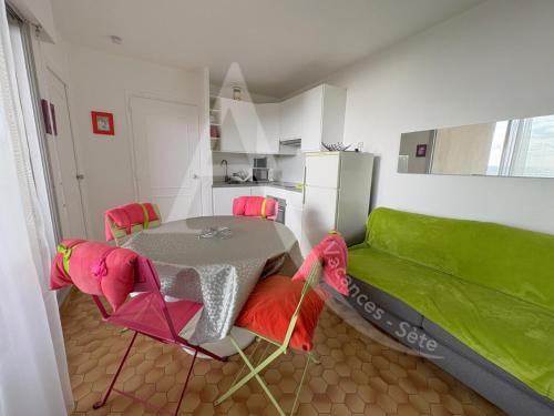 une cuisine avec une table et un canapé vert dans l'établissement coquet appartement 1 chambre avec parking bord de plage, à Sète