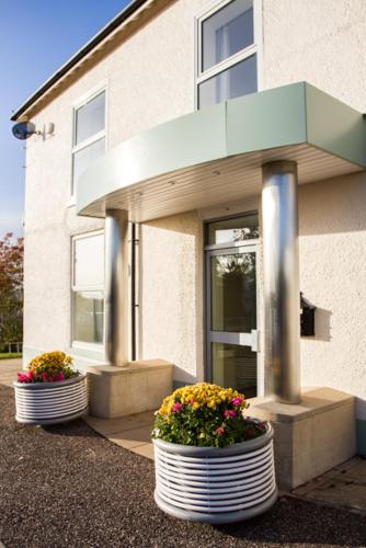 two pots of flowers in front of a building at Fair Oak House Exeter Airport in Exeter