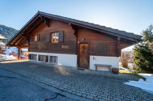 a wooden house with a door on a brick driveway at Akwaaba in Gryon