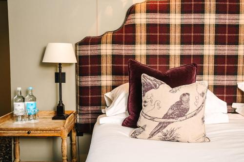 a bedroom with a bed with a plaid headboard at The Lygon Arms - an Iconic Luxury Hotel in Broadway
