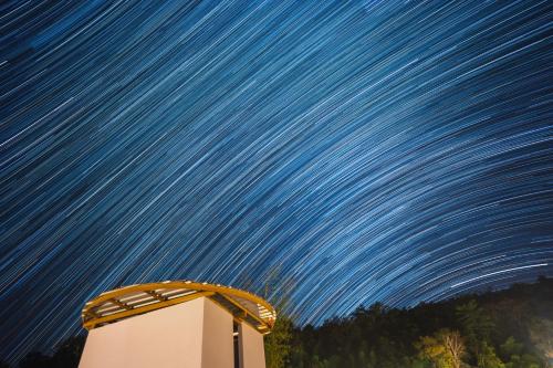 a starry sky with a building under it at Daraga ดารกะ in Chiang Dao