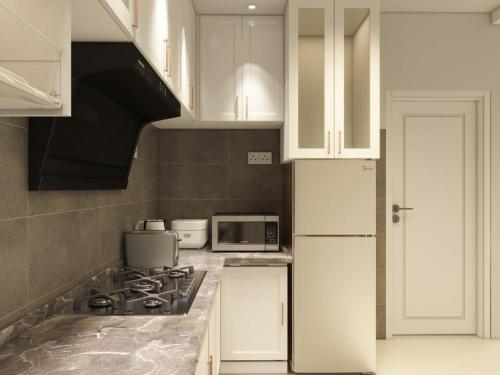 a kitchen with white cabinets and a stove top oven at Puteri Residence in Kuala Terengganu