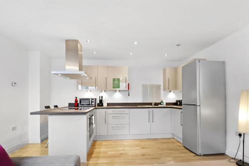 a kitchen with white cabinets and a stainless steel refrigerator at Portfolio Apartments - Stevenage Town Centre in Stevenage