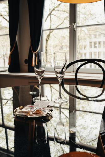 two wine glasses sitting on a table in front of a window at 1637: Historic Canal View Suites in Amsterdam