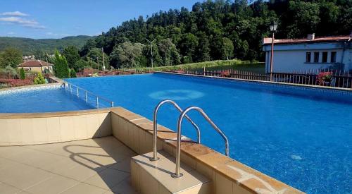 a large swimming pool with blue water at Rebeka Luxury Apartment in Tryavna