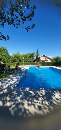 a blue swimming pool with a person sitting next to it at Cabañas Calderón II in San Rafael