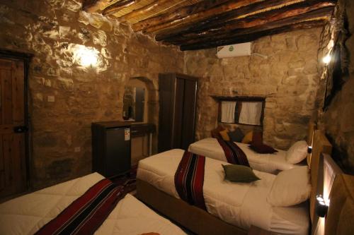 a bedroom with two beds and a stone wall at Hartna zaman in Taiyiba