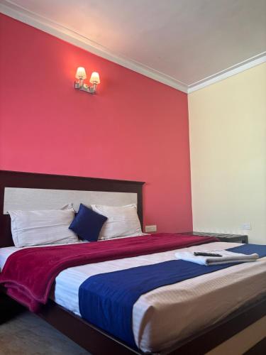 a bedroom with a large bed with a red wall at Golden Larch Comfort in Ooty