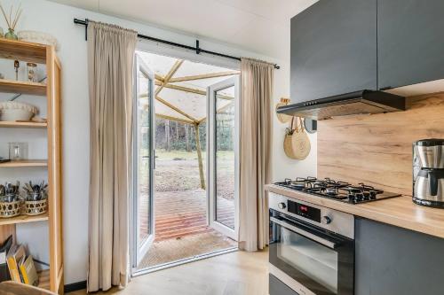 a kitchen with a stove and a sliding glass door at Cozy Chalet w terrace in the Middle of the Forest in Veluwe in Doornspijk