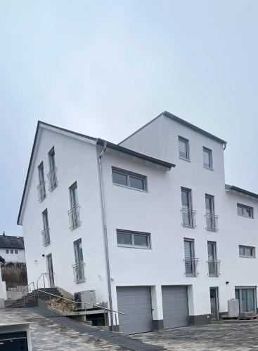 a large white building with two garage at Neubau Donaublickapartments in Sinzing