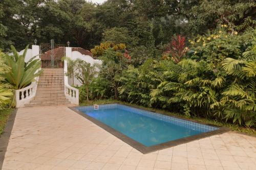 a swimming pool in the middle of a garden at ELIVAAS Maison 10 - Luxe 4 BHK Villa With Pvt Pool, Garden & Portuguese Charm in Siolim