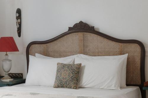a bed with a wooden head board and white pillows at ELIVAAS Maison 10 - Luxe 4 BHK Villa With Pvt Pool, Garden & Portuguese Charm in Siolim
