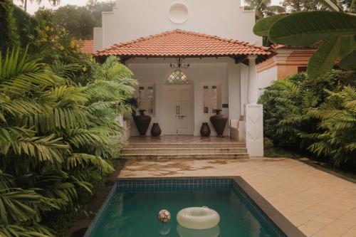 a house with a swimming pool in front of a house at ELIVAAS Maison 10 - Luxe 4 BHK Villa With Pvt Pool, Garden & Portuguese Charm in Siolim